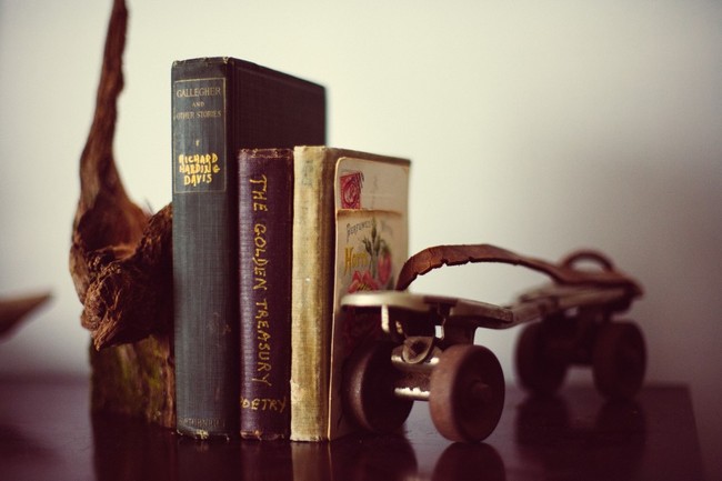 A display of three books propped by a piece of wood and a roller skate on either side. Intangible indexing terms could include e.g. leisure, memento, roller skates and display.